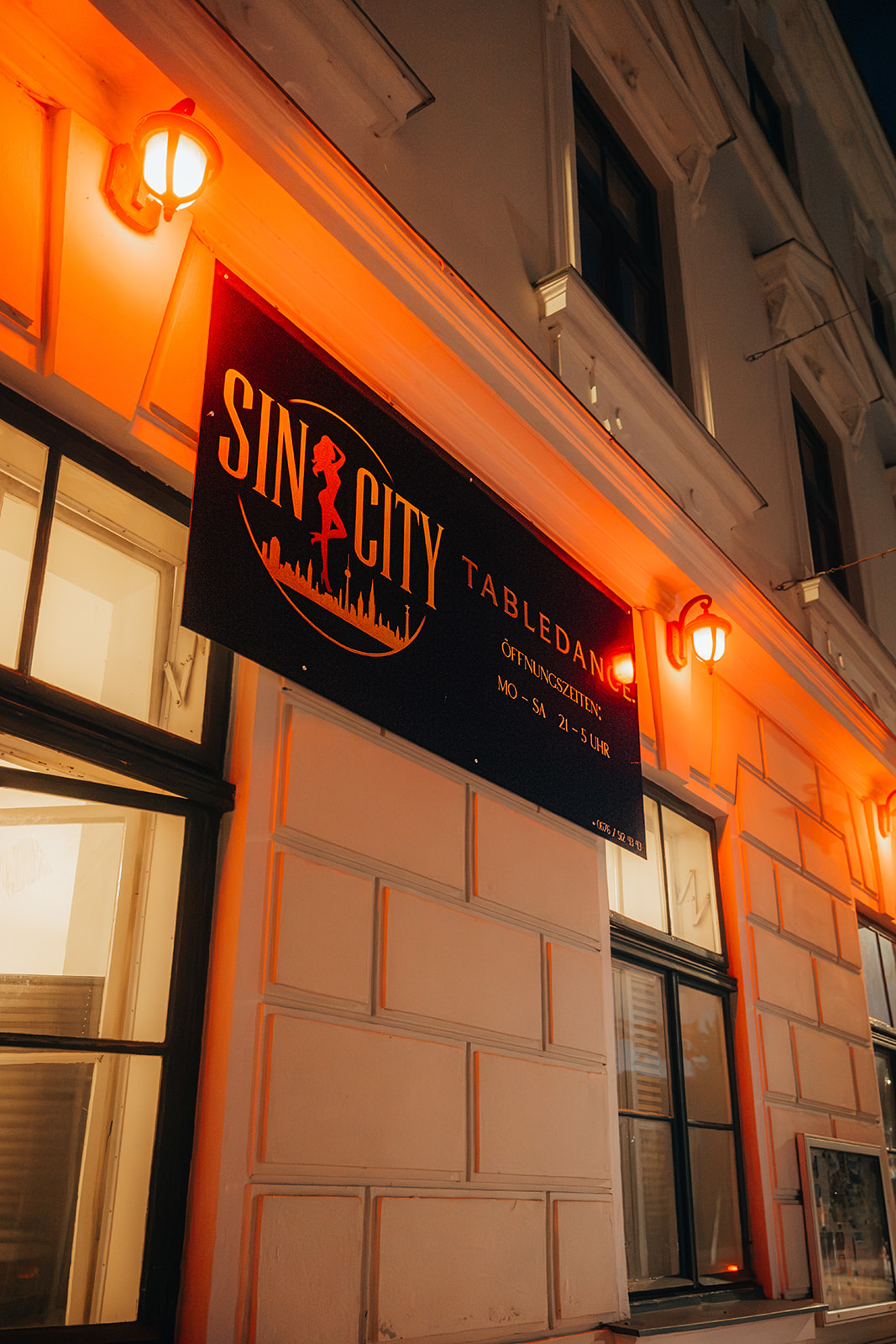 Nahaufnahme des Sin-City-Tabledance-Schildes an der Hauswand bei Nacht