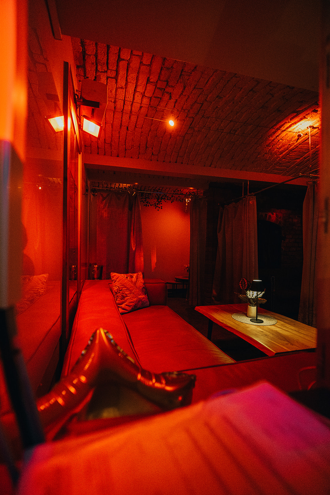 Sitzecke mit rotem Sofa und Holztisch unter einem Ziegelgewölbe