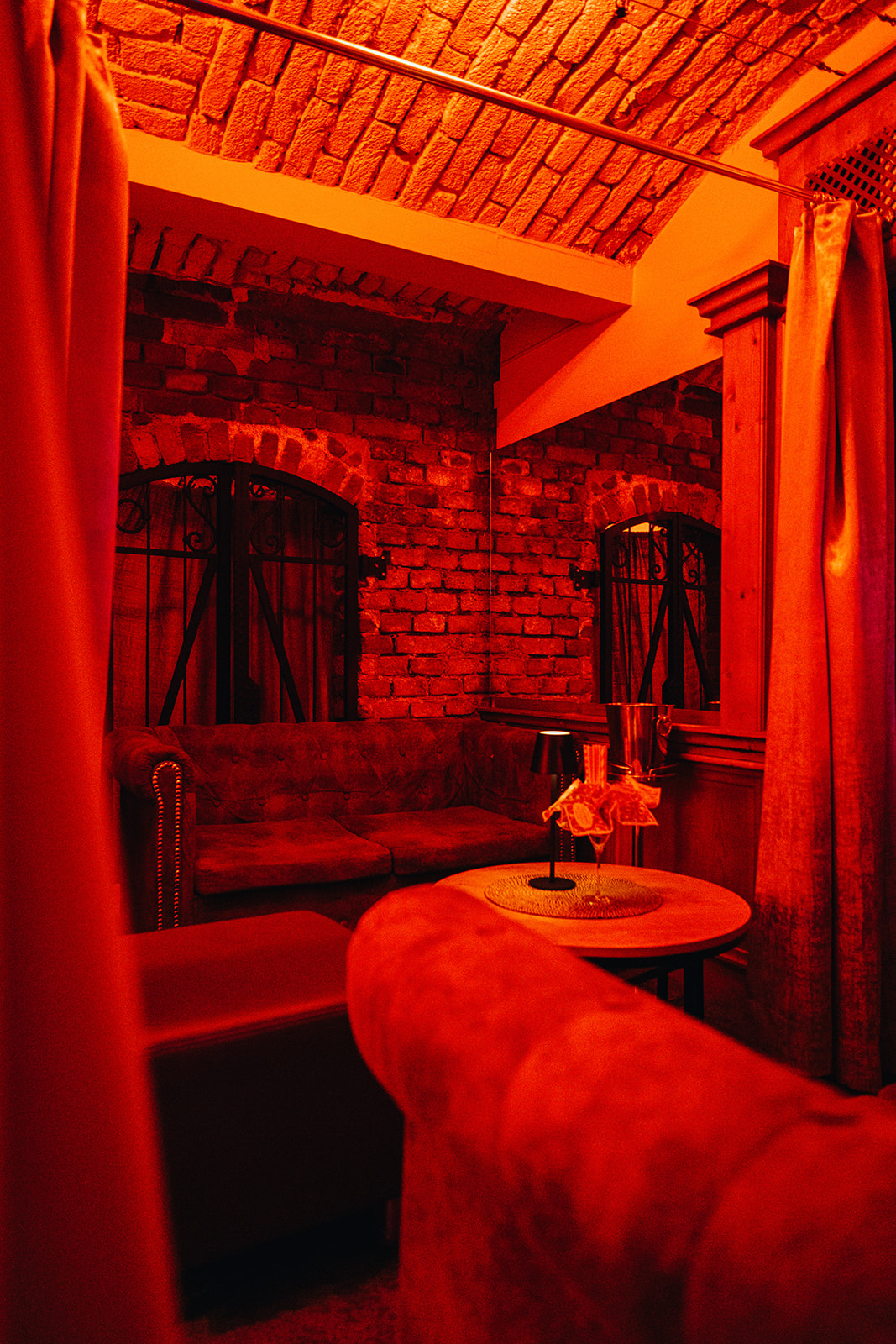 Private Lounge-Nische mit Sofa, Couchtisch und Champagnerkübel im roten Licht